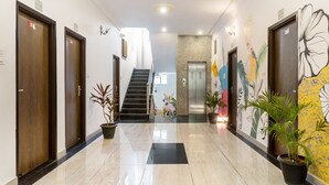 A hotel lobby with a marble floor, wooden doors, a staircase, and a wall mural. - Treebo The Fresco Lake Pichola (Udaipur)