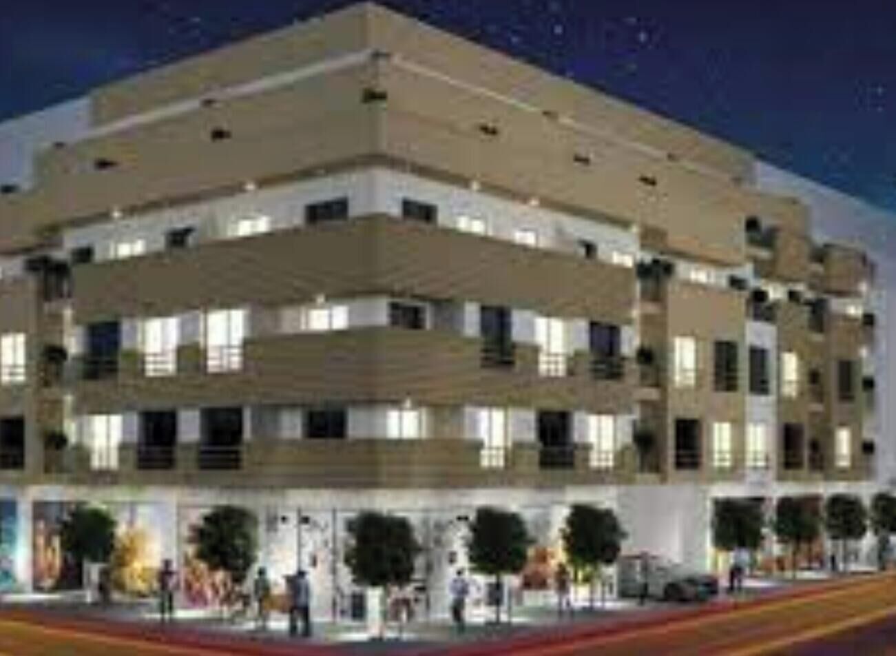 A multi-story hotel with a flat roof, numerous windows, and a ground-level entrance with a red carpet.