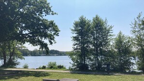 A grassy area with a wooden bench and a view of a lake. - Maison Chiche charming apartment 3 * 8 pers (Bain-de-Bretagne)