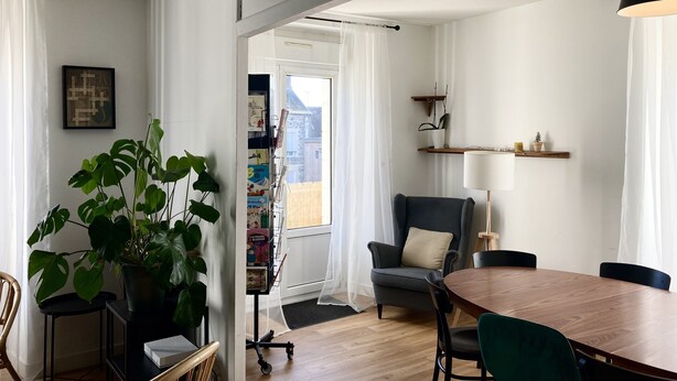 A modern living room with a wooden dining table, a grey armchair, and a large green plant. - Maison Chiche charming apartment 3 * 8 pers (Bain-de-Bretagne)