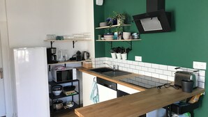 A compact kitchen with a white refrigerator, wooden countertop, and a green backsplash. - Maison Chiche charming apartment 3 * 8 pers (Bain-de-Bretagne)