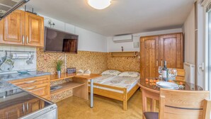 Uma cozinha compacta com armários de madeira, um fogão e uma mesa de jantar com uma cama ao centro.