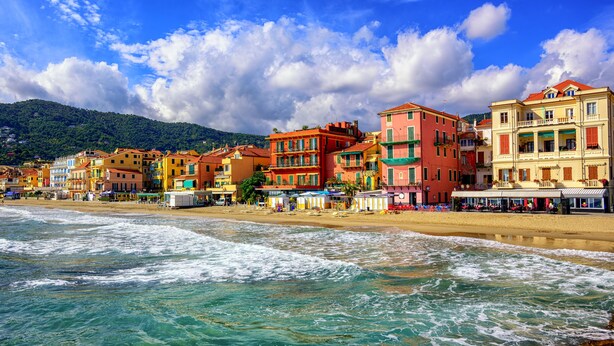 A coastal town with colorful buildings along the beach, clear blue waters, and a mountainous backdrop. - Tre Balconi Sul Mare - Beachfront Sea-view Apartment (Borghetto Santo Spirito)