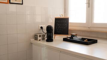 Un piano di lavoro in cucina con una macchina da caffè, un tostapane e una lavagna con scritte.