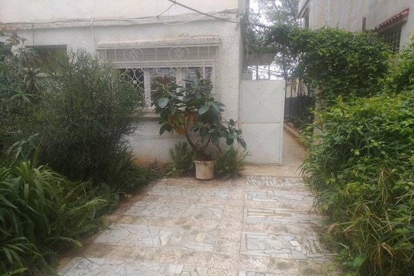 A paved pathway leading to a building with a window and a door.