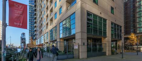 A modern building with large windows and a red banner advertising new homes available at a sales hub.