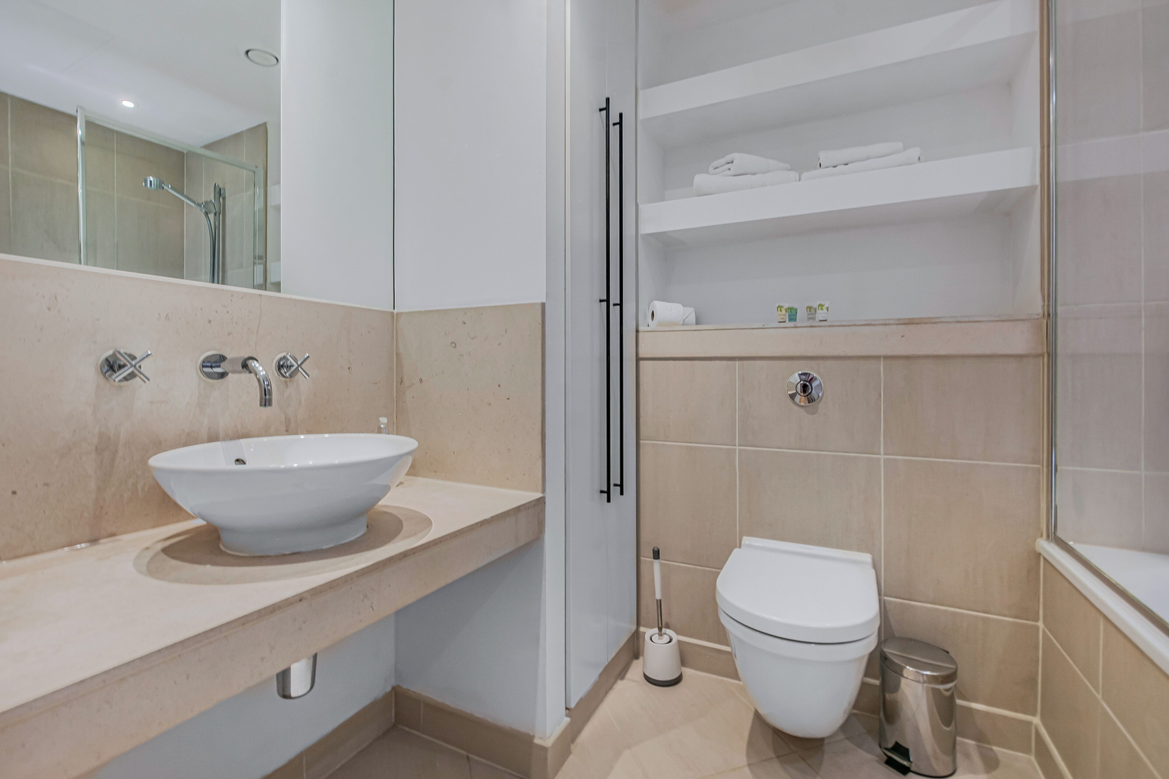 Une salle de bain moderne avec un grand lavabo blanc, des toilettes et une douche à parois de verre.