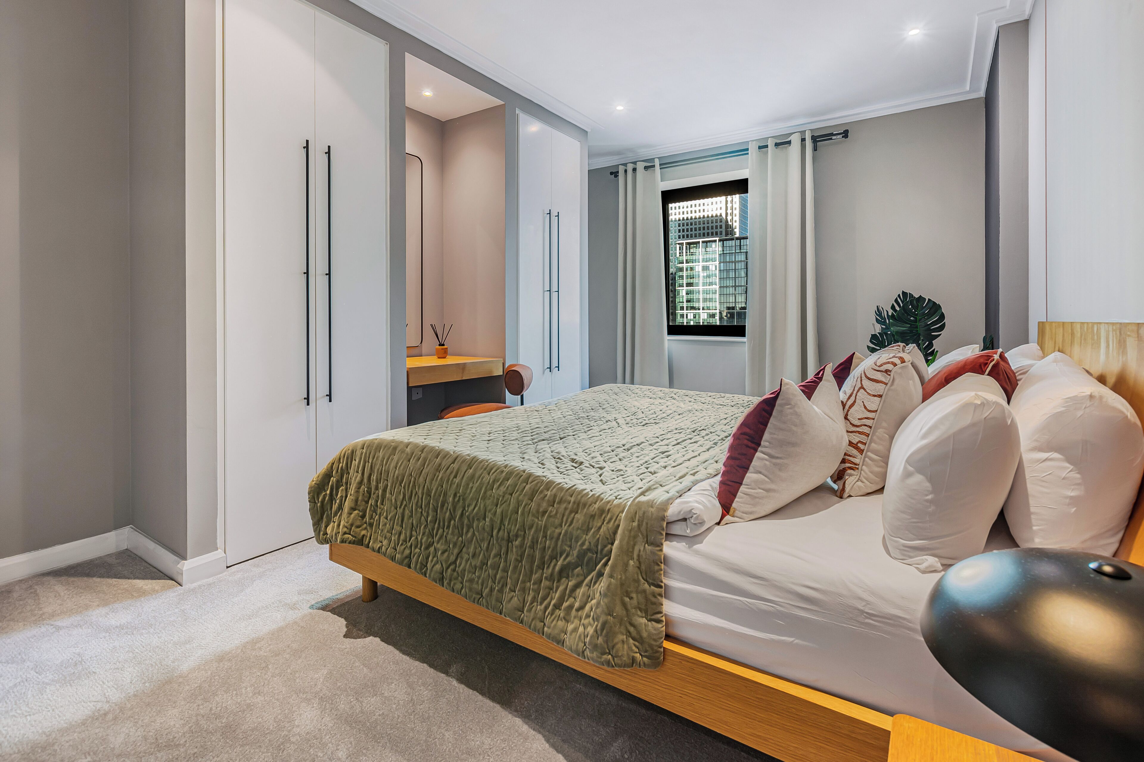 A modern bedroom with a bed, bedside table, and a window with curtains.
