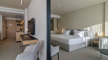 A modern hotel room with a bed, a desk, a chair, and a small table.