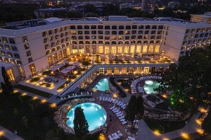 Un hotel con varias piscinas, zonas de estar al aire libre y un patio bien iluminado.