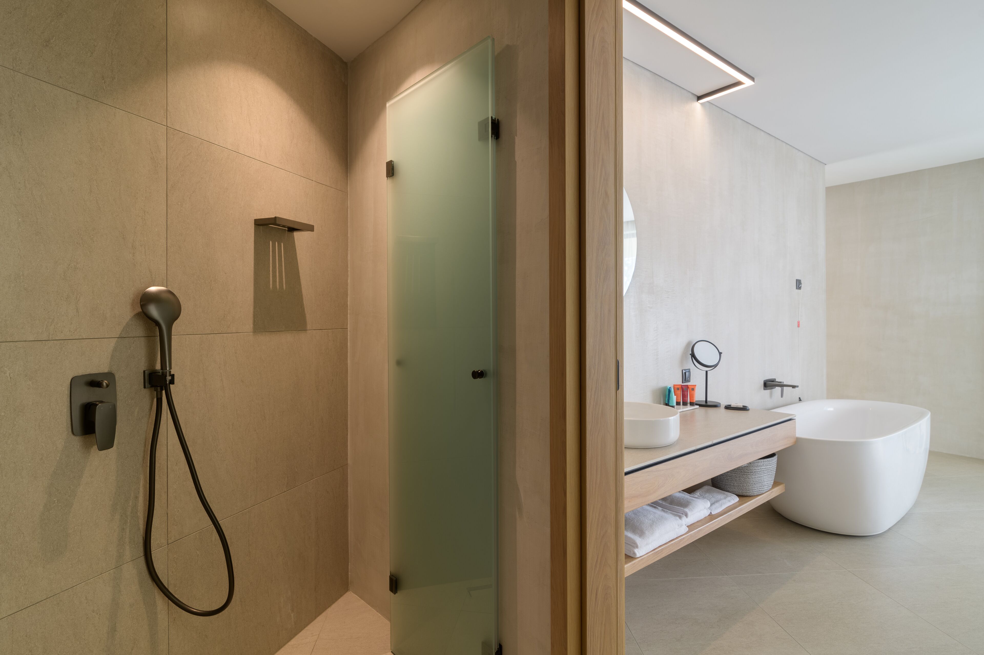 A modern bathroom with a glass shower enclosure, a freestanding bathtub, and a vanity with a mirror.