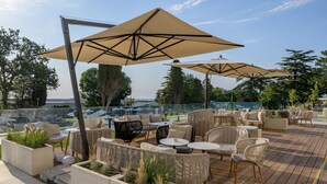 Une terrasse extérieure aménagée avec des meubles en osier, des coussins beiges et de grands parasols.