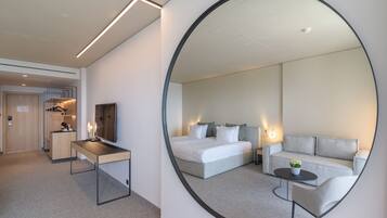 Een hotelkamer met een grote spiegel, een bed, een bank, een bureau en een kleine tafel.