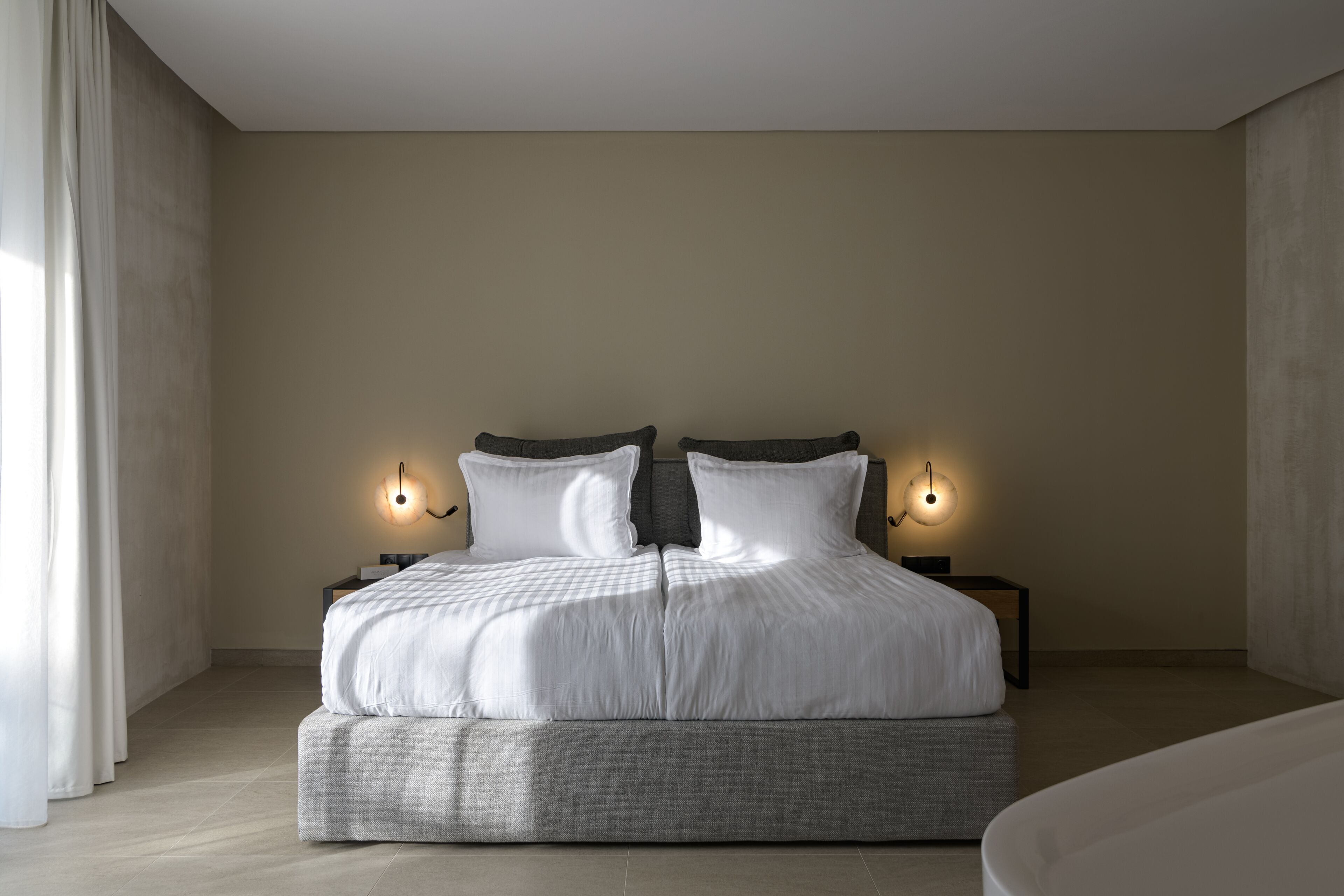 A modern bedroom with a large bed, two bedside tables, and a nightstand.