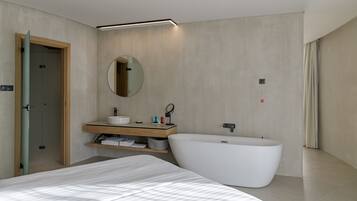 Un baño moderno con una bañera independiente, un espejo redondo y un tocador de madera.
