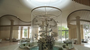 Un hall d’entrée spacieux, agrémenté d’une fontaine centrale en verre, de coins salon et de grandes fenêtres laissant entrer la lumière naturelle.