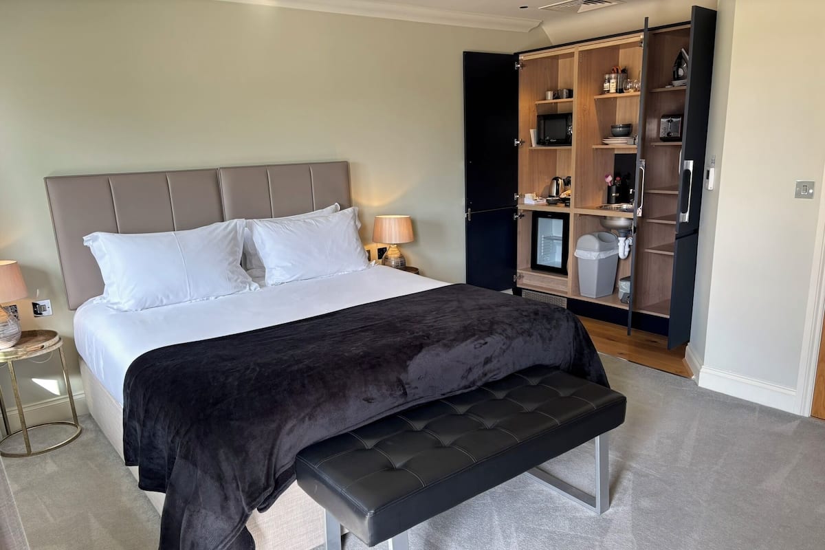 A bedroom with a bed, bedside table, lamp, and a wardrobe with shelves.