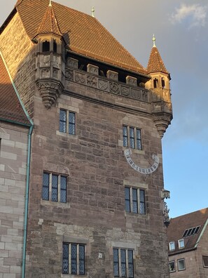Ein historisches Gebäude mit einem Uhrturm, einer steinernen Fassade und zahlreichen Fenstern.