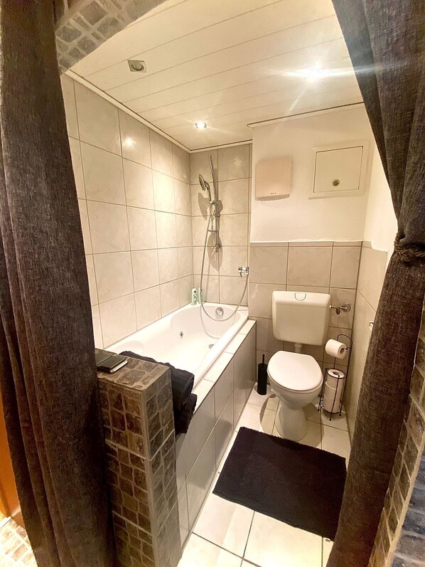 A bathroom with a bathtub, toilet, and shower.