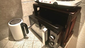 A compact kitchen with a gas stove, a kettle, and a sink.