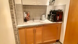 A compact kitchen with a sink, countertop, and cabinets.