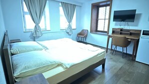 Una habitación con una cama, un escritorio, una silla y un televisor.