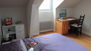 Una camera da letto con un letto, una scrivania, una sedia, un termosifone e una finestra.