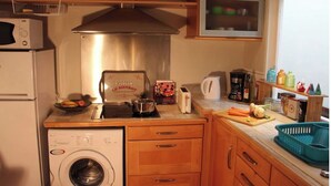 Una cucina compatta con lavatrice, tostapane, bollitore e diversi utensili ed elettrodomestici.