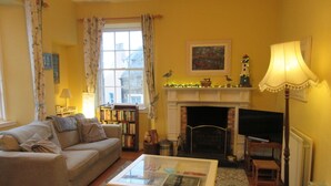 A living room with a sofa, a coffee table, a fireplace, a television, and a bookshelf.