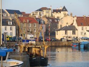 A harbor with boats, a crane, and buildings in the background.