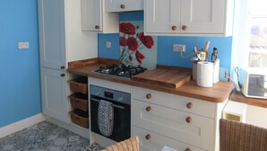 A kitchen with blue walls, white cabinets, a gas stove, and a microwave.