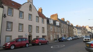 A street lined with historic buildings, parked cars, and a clear sky.