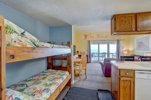 A room with bunk beds, a dining area, and a view of the sea. - 2 Bedroom Oceanfront Condo with Beautiful Views (Holly Ridge)