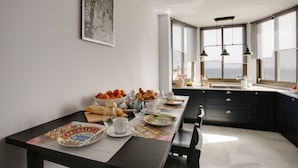 Une cuisine moderne avec une table à manger dressée pour le petit-déjeuner, avec des croissants, des oranges et une tasse de café.