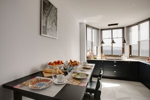 Een moderne keuken met een ontbijtstafel, compleet met croissants, sinaasappels en een koffiekop.