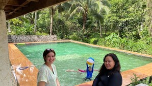 A pool area with a stone wall and lush greenery in the background. - Farmstead vacation house in the middle of Sabang and Dinadiawan beach (Dipaculao)