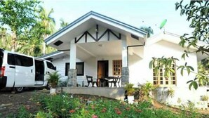 A white house with a porch, a dining area, and a garden with flowers. - Farmstead vacation house in the middle of Sabang and Dinadiawan beach (Dipaculao)
