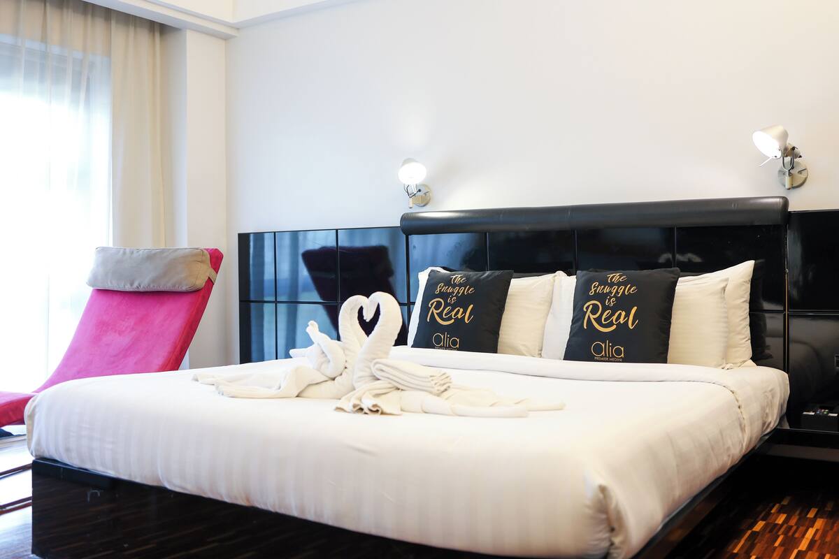A neatly made bed with white linens and two pillows with gold text.