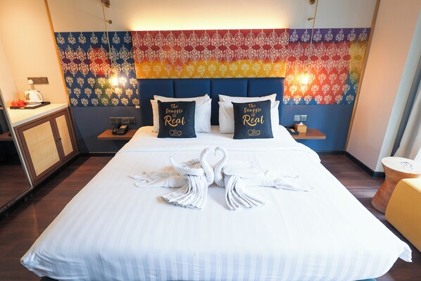 A hotel room with a neatly made bed, two pillows with text, a tapestry on the wall, and a small table with a lamp. - Alia Premier KLCC (Kuala Lumpur)