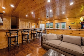 A wooden interior with a bar area, seating, and a sofa.