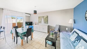 A modern living room with a dining area, a sofa, a coffee table, and a TV. - Hyères T2 5mn plage Almanarre CLiM/PK/WiFi (HYERES)