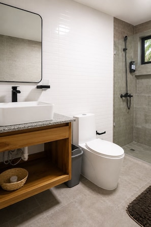 A modern bathroom with a white sink, toilet, and shower.