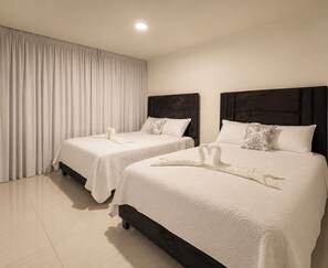 A hotel room with two beds, a large window with curtains, and a ceiling light.