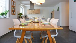 Un espace repas moderne avec une table en bois dressée pour six personnes, entourée de chaises blanches.