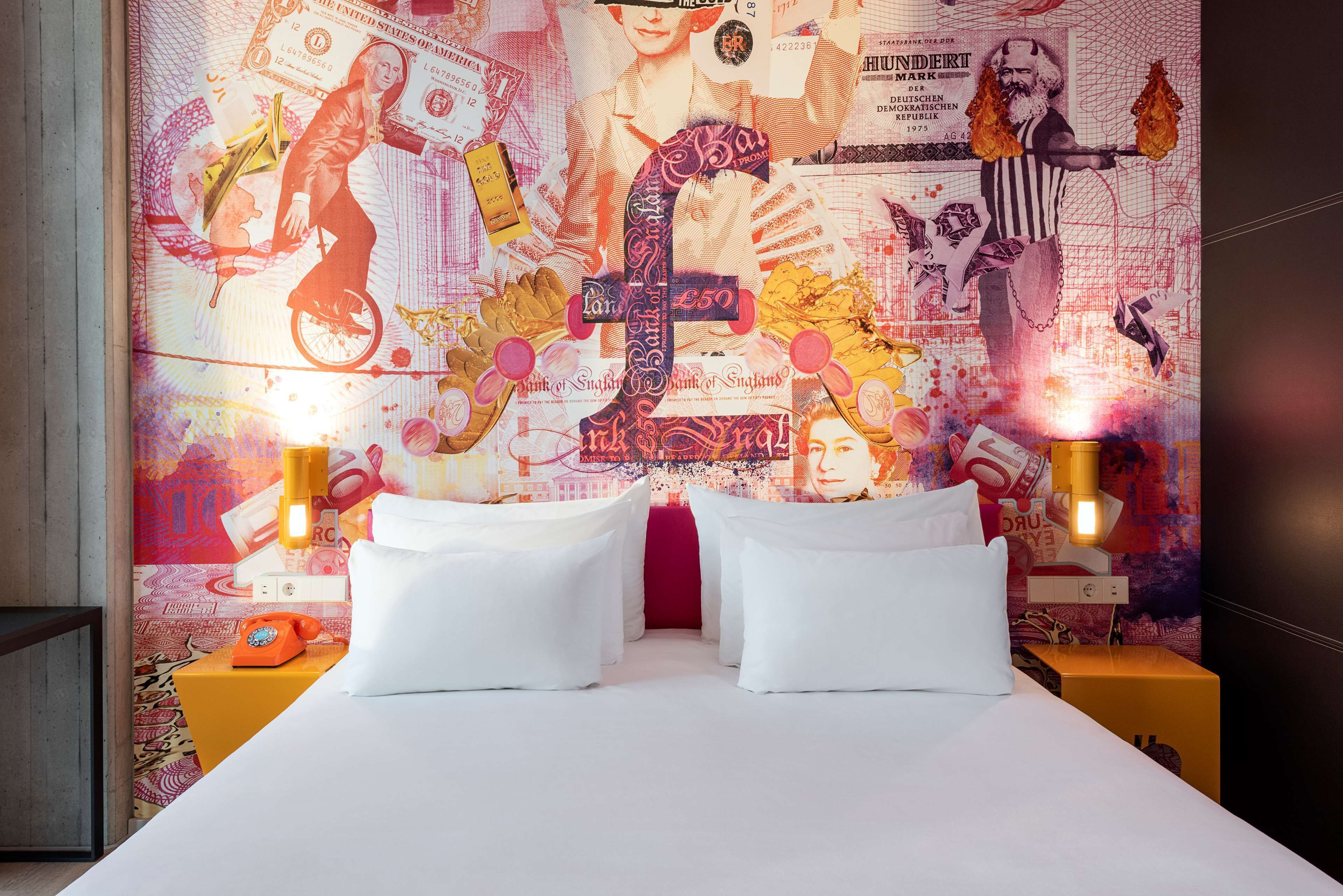 A hotel room with a large bed, two bedside tables, and a wall covered with a vibrant, artistic design.