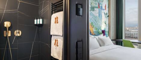 A hotel room with a bed, a shower area, and a wall with a map.