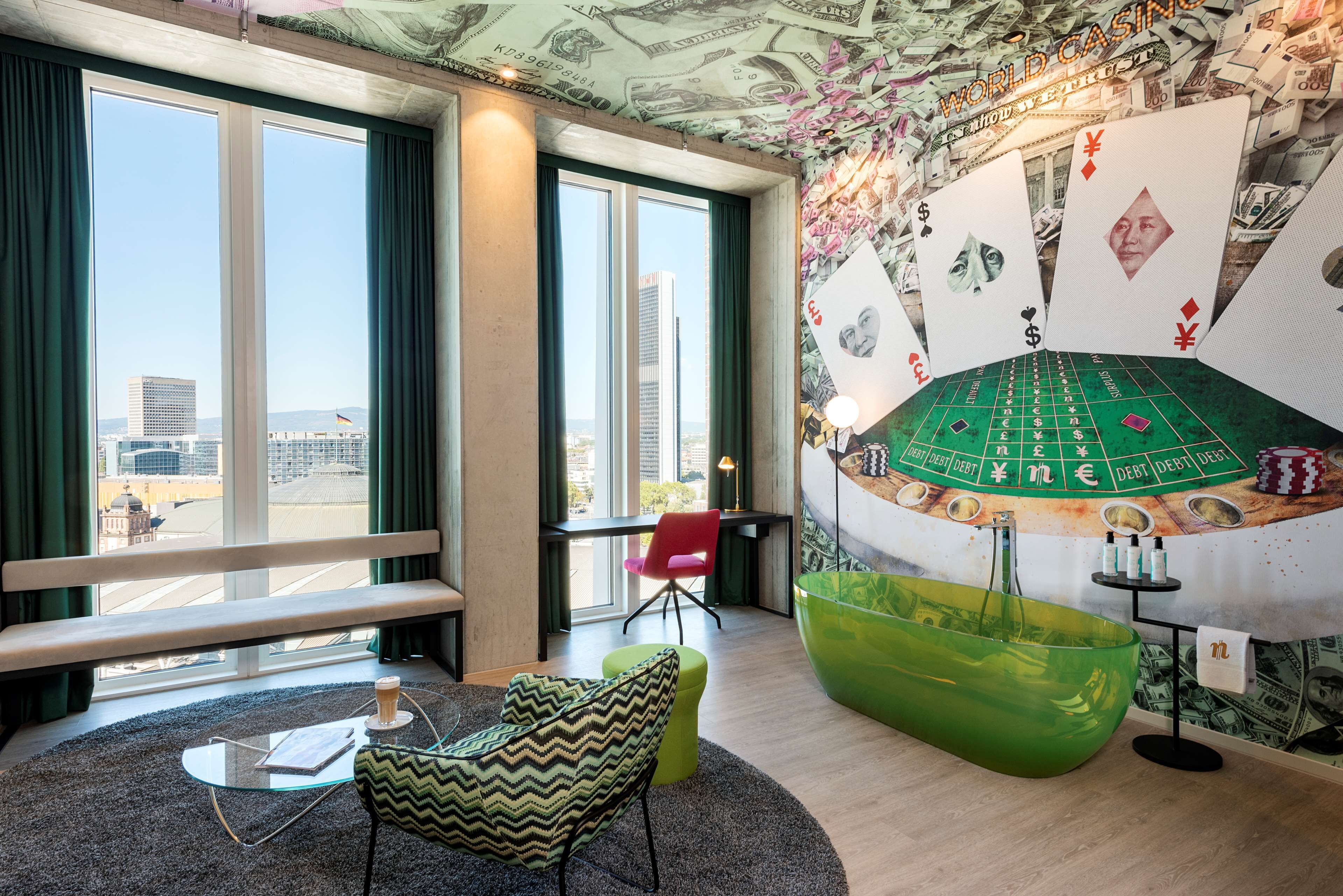 Ein modernes Zimmer mit großen Fenstern, einer grünen Badewanne und einer Wandmalerei mit Roulette-Motive.