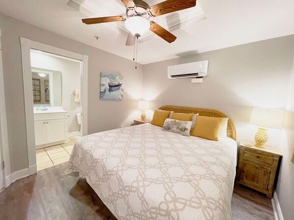 Une chambre à coucher comprenant un lit, un ventilateur de plafond, un climatiseur, une table de chevet et une commode.