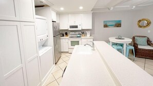 Una cocina moderna con armarios blancos, una isla central y un comedor con una mesa redonda y sillas.