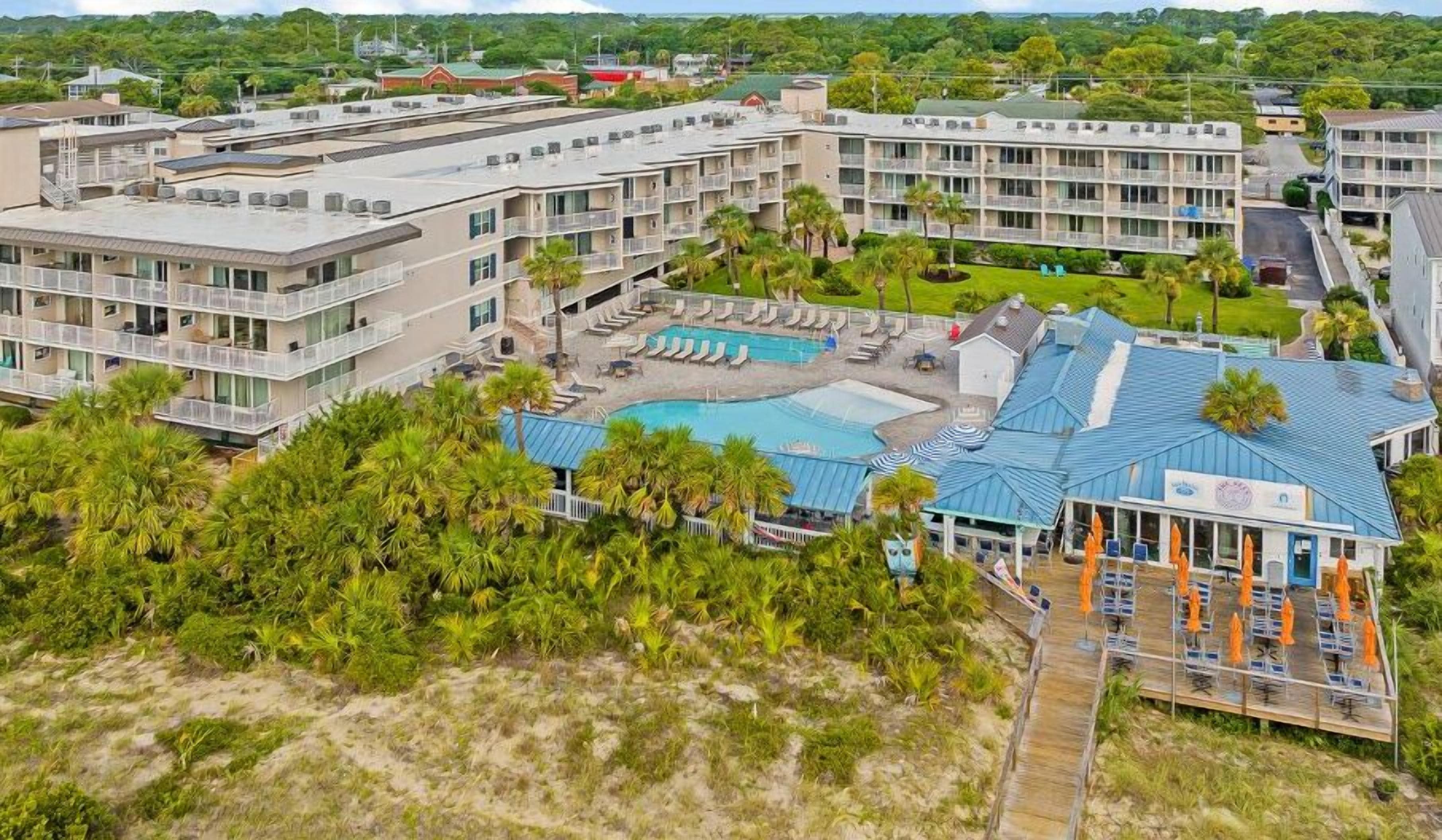 Un hôtel à plusieurs étages doté d’une piscine, d’un espace extérieur aménagé et offrant une vue sur la plage.